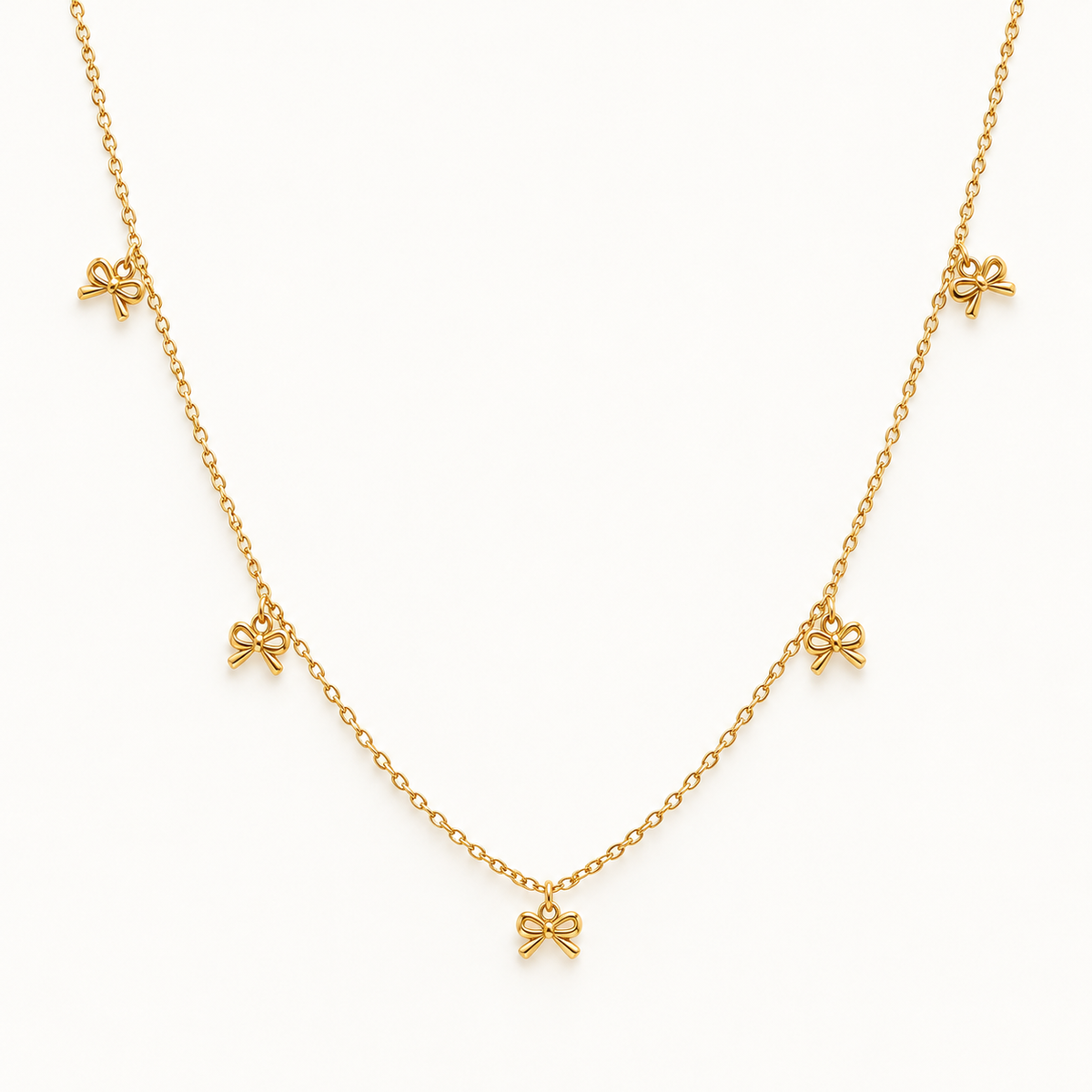 Gouden strikjesketting op ivoorachtergrond – The Delicate Bow | Enjoia