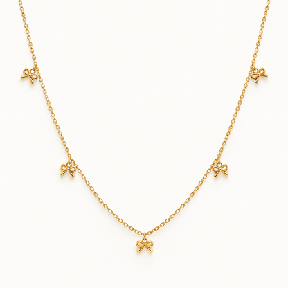 Gouden strikjesketting op ivoorachtergrond – The Delicate Bow | Enjoia