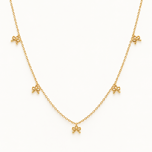 Gouden strikjesketting op ivoorachtergrond – The Delicate Bow | Enjoia