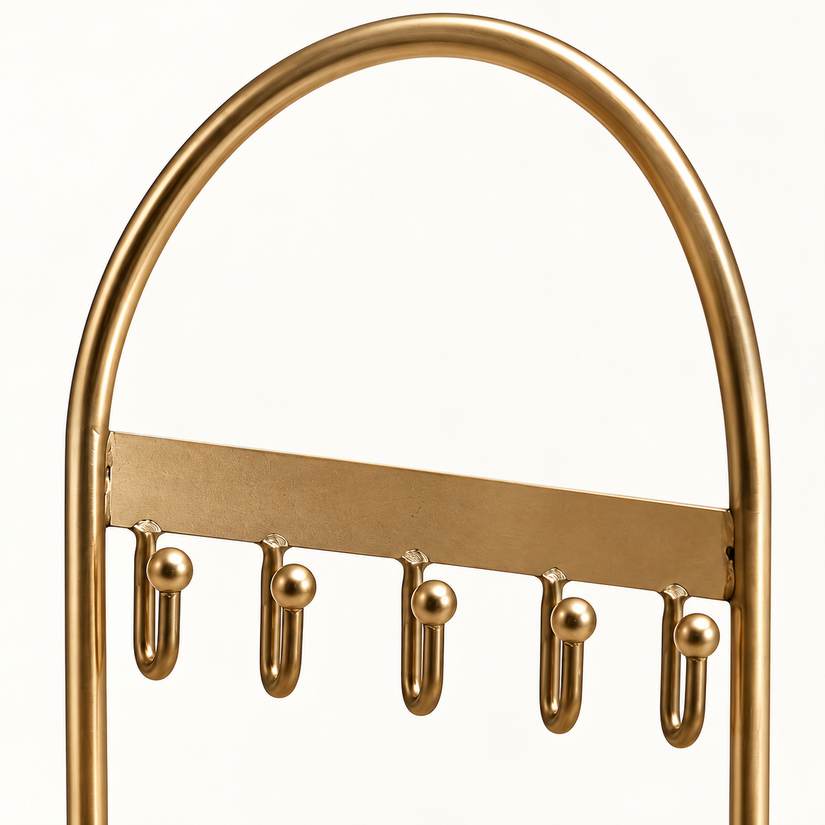 Detail van het gebogen goudkleurige frame en de ophanghaakjes van de sieradenhouder